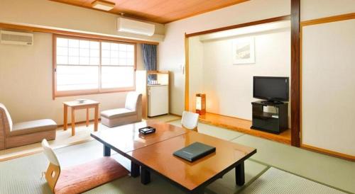 a living room with a table and a tv at Yuzawa New Otani in Yuzawa