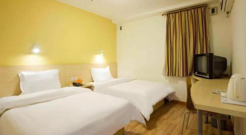 a hotel room with two beds and a television at 7 Days Inn Yiyang Shengli Road in Shangrao
