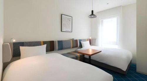 a hotel room with two beds and a window at Hotel Edit Yokohama in Yokohama