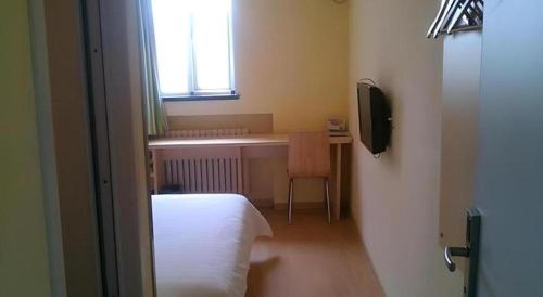 a room with a bed and a desk and a television at 7 Days Inn Qingdao Si Liu South Road in Qingdao