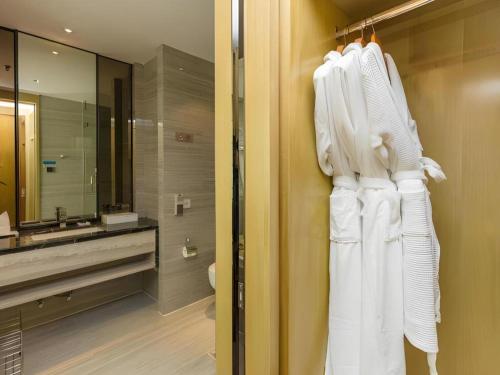 a bathroom with a white robe hanging on a wall at Huafa Executive Apartment Hotel Zhuhai in Zhuhai