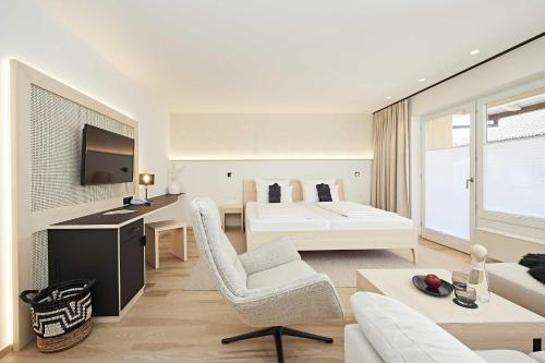 a white room with a bed and a couch and a table at Hotel Rosenstock - Erwachsenenhotel - Adults only 15 plus in Fischen