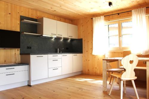 a kitchen with white cabinets and a table and chairs at Gögelehof in Stulles