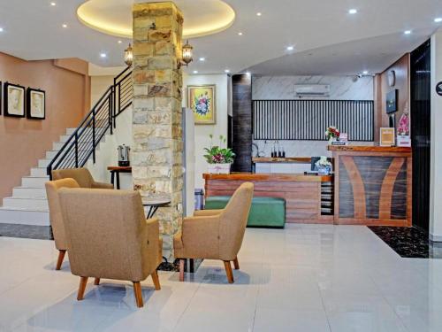 a lobby with a table and chairs and a staircase at Raja Soeta Express Syariah in Hajimana