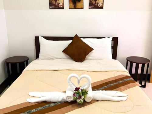 a bed with two white slippers and a bouquet of flowers at Rueangrat Hotel in Ranong
