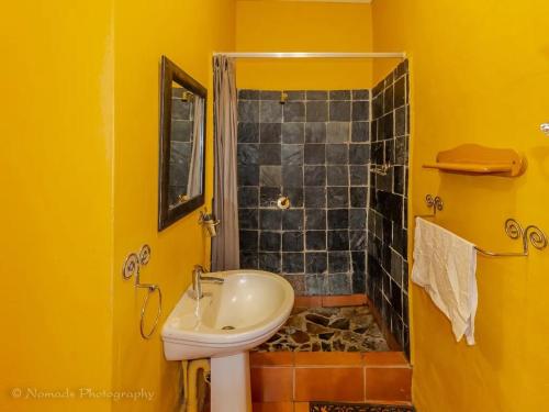 a yellow bathroom with a sink and a shower at KwaThabisile Bush Retreat in Cullinan