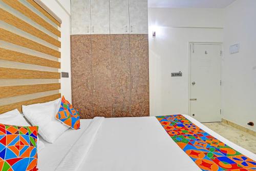 a bedroom with a white bed with a colorful blanket at FabHotel Metro Grand - Koramangala in Bengaluru