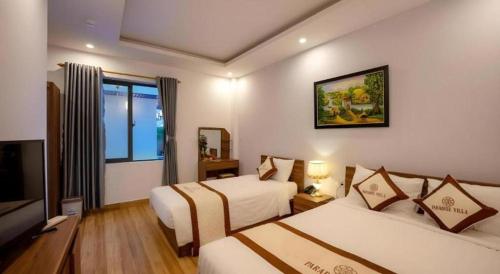 a hotel room with two beds and a television at Hoi An Paradise Villa in Hoi An