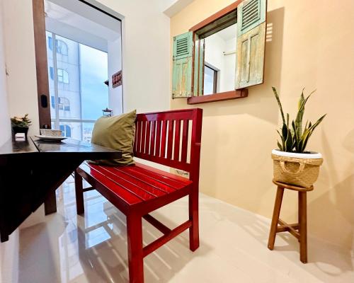a red bench in a room with a desk and a plant at Cozy 2BR Apartment in City Square East Surabaya by Le Ciel Hospitality in Surabaya