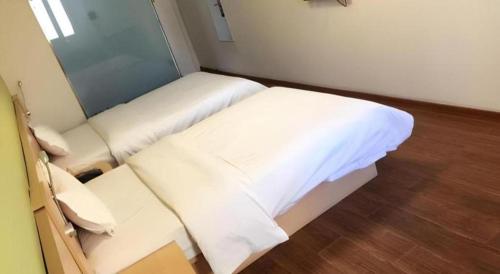 a small room with a bed with white sheets at 7 Days Inn West Gate of Taiyuan University of Technology in Taiyuan