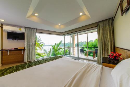 a bedroom with a large bed and a large window at Nopparat Garden in Samut Songkhram