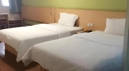 two beds in a hotel room with white sheets at 7 Days Inn West Gate of Taiyuan University of Technology in Taiyuan