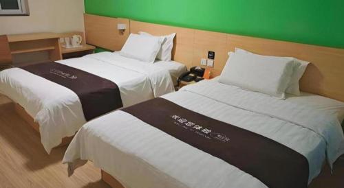 two beds in a hotel room with a green wall at 7 Days Inn West Gate of Taiyuan University of Technology in Taiyuan