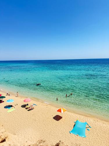 een strand met parasols en mensen in het water bij Casa Mare Salento - a due passi dal mare in Marina di Lizzano