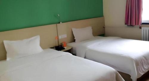 two beds sitting next to each other in a room at 7 Days Inn Guangrao Bus Station in Dongying