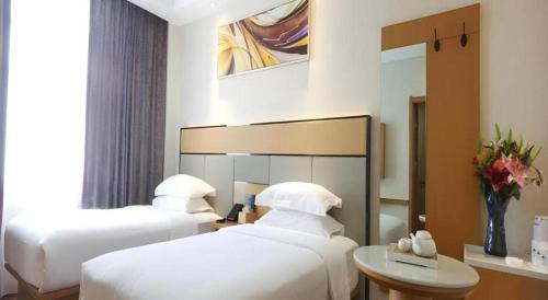 a hotel room with two beds and a mirror at GreenTree Inn Geermu Walking Street Business Hotel in Golmud