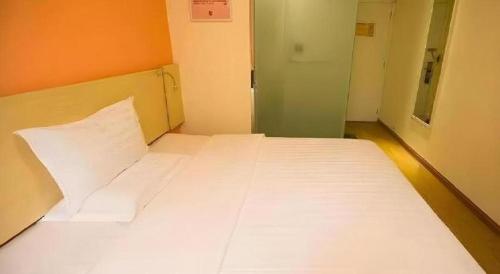 a large white bed in a small room at 7 Days Inn Guangrao Bus Station in Dongying