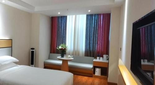 a bedroom with a bed and a bench and a window at GreenTree Inn Geermu Walking Street Business Hotel in Golmud