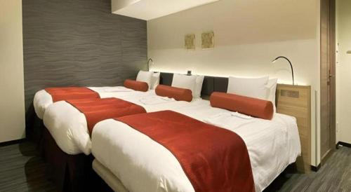 a hotel room with two beds with red and white sheets at KEIKYU EX INN Hamamatsucho Daimon-Station (Tokyo) in Tokyo