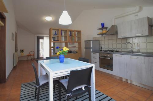 een keuken met een witte tafel met stoelen en een blauwe vaas bij Casa Guglielmo in Viareggio