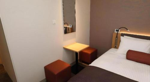 a small bedroom with a bed and a desk at KEIKYU EX INN Tokyo Nihombashi in Tokyo