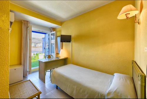 a bedroom with a bed and a desk and a window at Hotel Marina in Oropesa del Mar