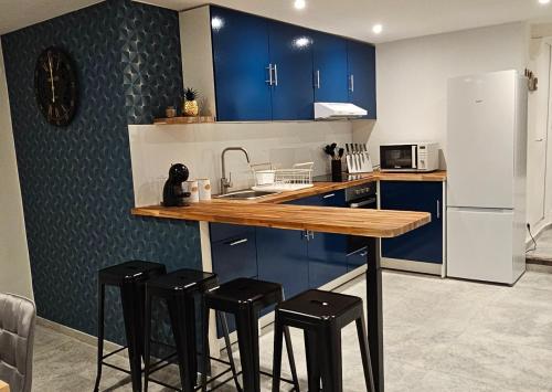 une cuisine avec des placards bleus et un comptoir avec des tabourets dans l'établissement Bel appartement et son jardin, à Saint-Cézaire-sur-Siagne