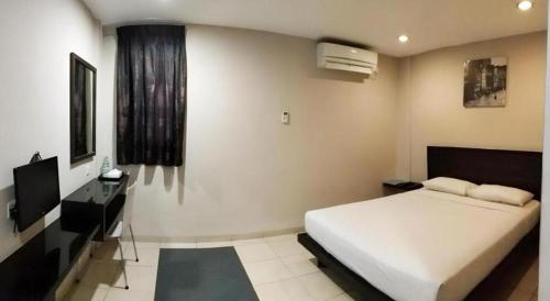 a bedroom with a bed and a desk and a television at Hotel Bintan Nirwana in Tanjung Pinang 