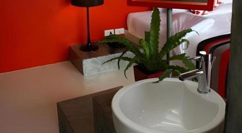 a bathroom with a sink and a plant next to a bed at The B Ranong Trend Hotel in Ranong