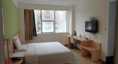 a hotel room with a bed and a desk and a television at 7Days Inn Xuzhou Normal University Yunlong Mountain in Xuzhou