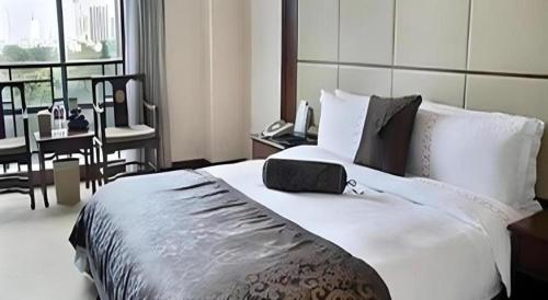 a bedroom with a large white bed with a desk at Liyuan Hotel in Shenzhen