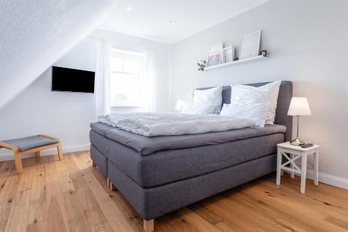 a bedroom with a bed and a chair and a window at Reethaus MeerFerien direkt am Wasser in Mellnitz