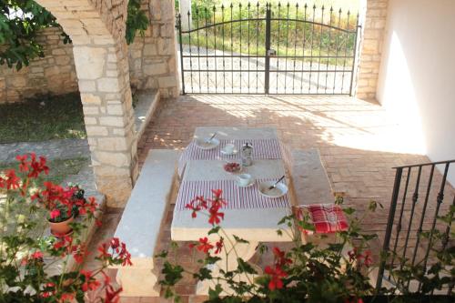 a picnic table in a courtyard with red flowers at Holiday Home Kukurin in Bale
