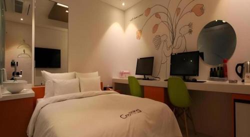 a bedroom with a bed and a desk with two monitors at Crossing Hotel in Seoul