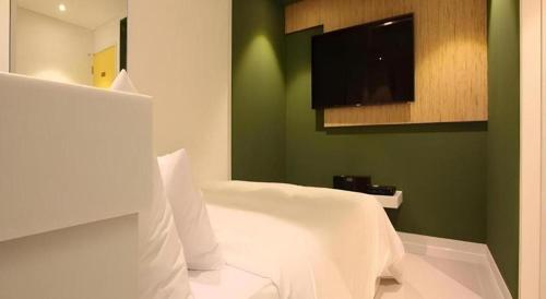 a bedroom with a white bed and a flat screen tv at Crossing Hotel in Seoul