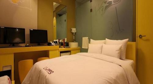 a bedroom with a bed and a desk with a computer at Crossing Hotel in Seoul