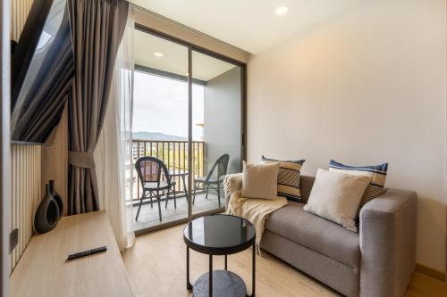 a living room with a couch and a balcony at The Ozone Residences Bangtao in Phuket