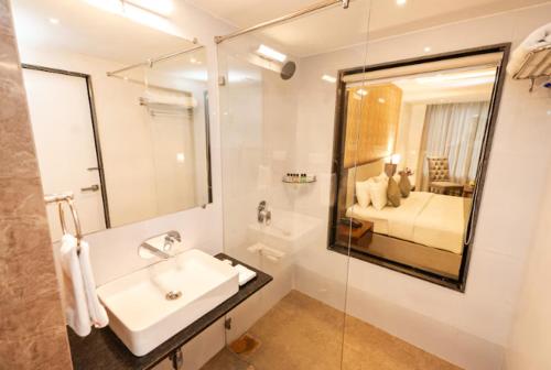 a bathroom with a sink and a bed and a mirror at The OAK Resort, Goa in Pilerne