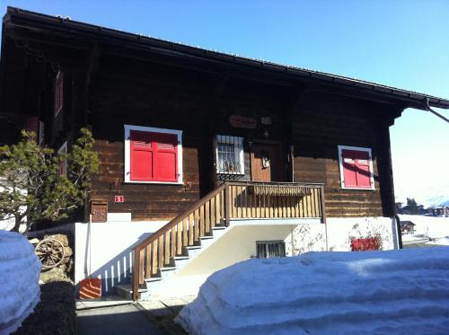 a log house with red windows and stairs in the snow at Uf em Schloss in Biel