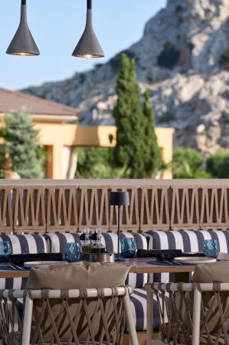 a table and chairs with a mountain in the background at Atlantica Aegean Blue in Kolimbia