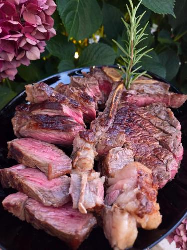 a pile of meat on a plate next to flowers at Hotel Ristorante al Giardinetto in Colle Umberto