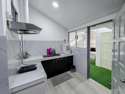 a white kitchen with a sink and a window at VV Rooms in Tawau