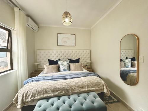 a bedroom with a bed with a blue ottoman and a mirror at 2 On Lismore Guesthouse in Tokai