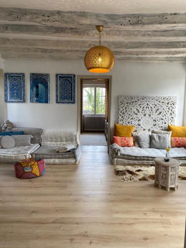 a living room with two couches and a chandelier at Les Carillons du Bois de l'Orme in Les Pechs-du-Vers