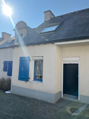 a white house with blue windows and a garage at Maison le clos du phare 3 in Quiberon