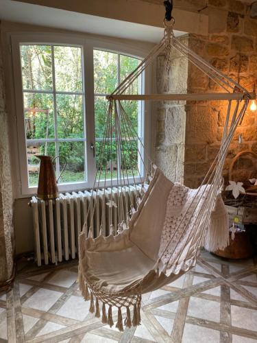 a hammock in a room with a stone wall at Les Carillons du Bois de l'Orme in Les Pechs-du-Vers