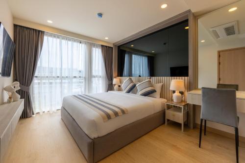 a hotel room with a large bed and a desk at The Ozone Residences Bangtao in Phuket