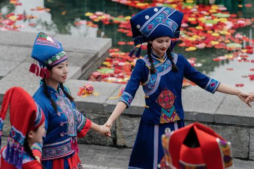 two young girls in traditional costumes standing in front of a pond at Banyan Tree Yangshuo in Yangshuo