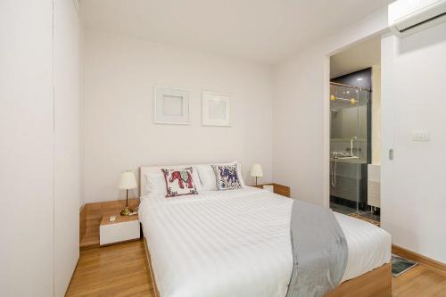 a white bedroom with a large white bed and a window at The Nimmana Condo 410 - Super Deluxe 1BR Balcony extension in Chiang Mai