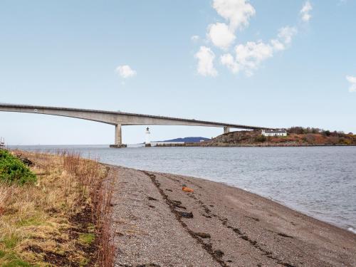 a bridge over a body of water with a road at Waterside Cottage in Kyleakin